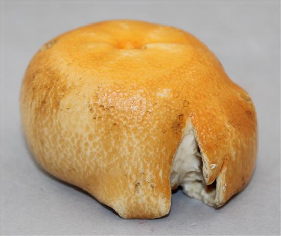A Japanese coloured ivory model of a partially peeled satsuma, early 20th century, 7cm.